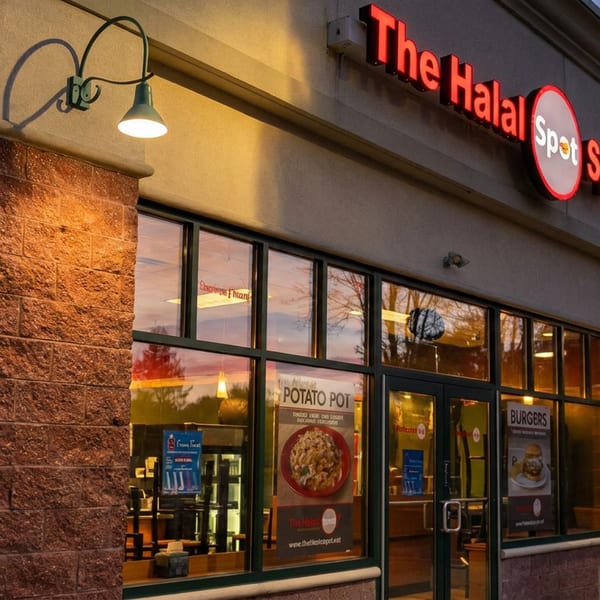 The Halal Spot restaurant exterior at dusk, with illuminated signage and window displays.